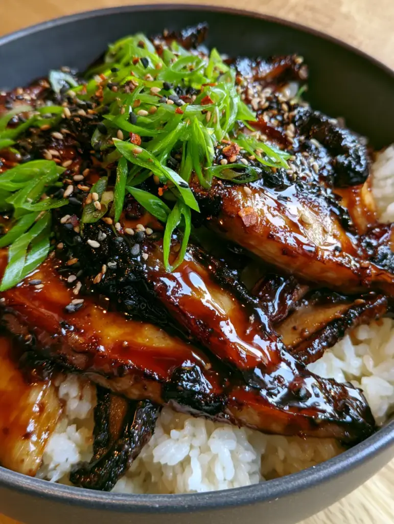 Detailed shot of scallions and sesame seeds atop a Teriyaki mushrooms and rice bowl with soft side lighting.
