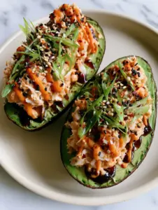 Close-up of chunky spicy crab salad piled into a ripe avocado with zig-zag sriracha mayo. (spicy crab stuffed avocado)
