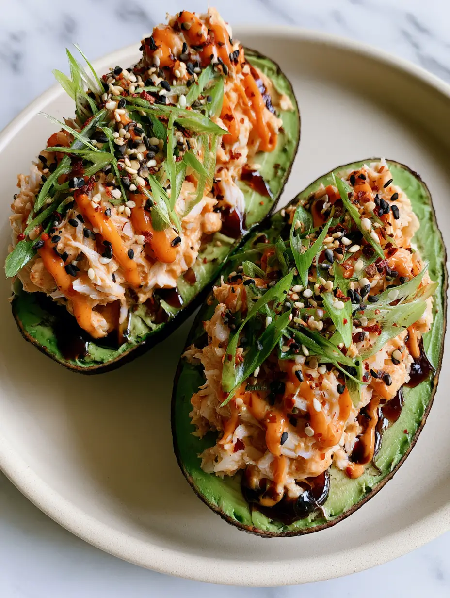Close-up of chunky spicy crab salad piled into a ripe avocado with zig-zag sriracha mayo. (spicy crab stuffed avocado)