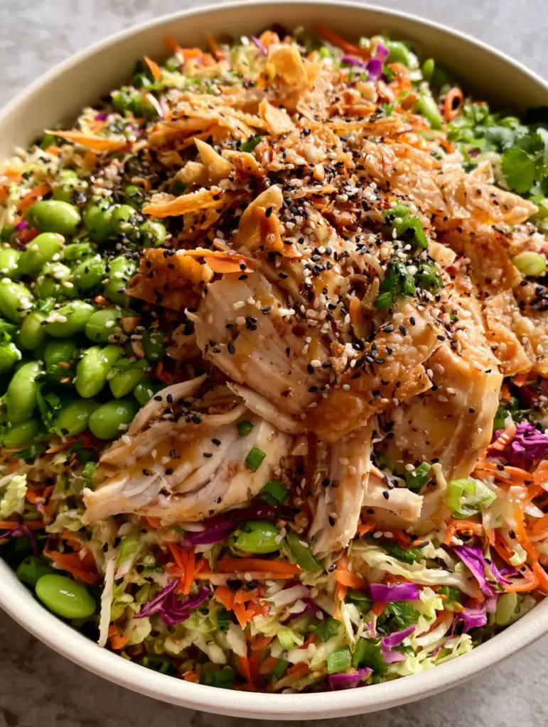 Asian Crunch Chicken Salad with Honey Ginger Vinaigrette 1 A vibrant Asian crunch chicken salad served on a neutral grey stone surface with fresh cilantro and bright green edamame.