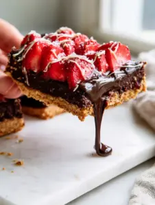 A hand lifting a gooey dark chocolate strawberry bar showing a long chocolate pull. (easy dessert recipes)