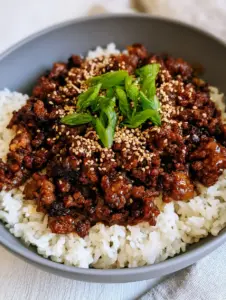 High-angle smartphone photo of a honey garlic beef rice bowl featuring extra-crispy mahogany brown beef and glossy glaze.