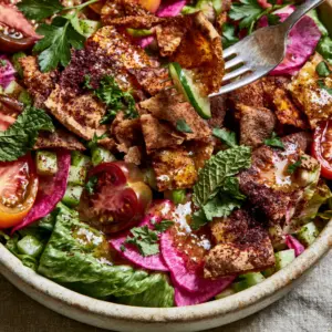 High-angle macro shot of a Middle Eastern salad in a cream bowl showing heirloom tomatoes and mint. (Middle Eastern salad)