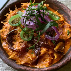 Extreme handheld close-up of Enugu Abacha showing the grainy texture of crayfish and vibrant orange palm oil emulsion. (Enugu Abacha)